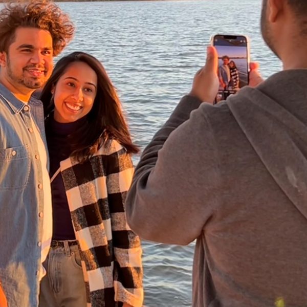 a couple of people standing next to a body of water